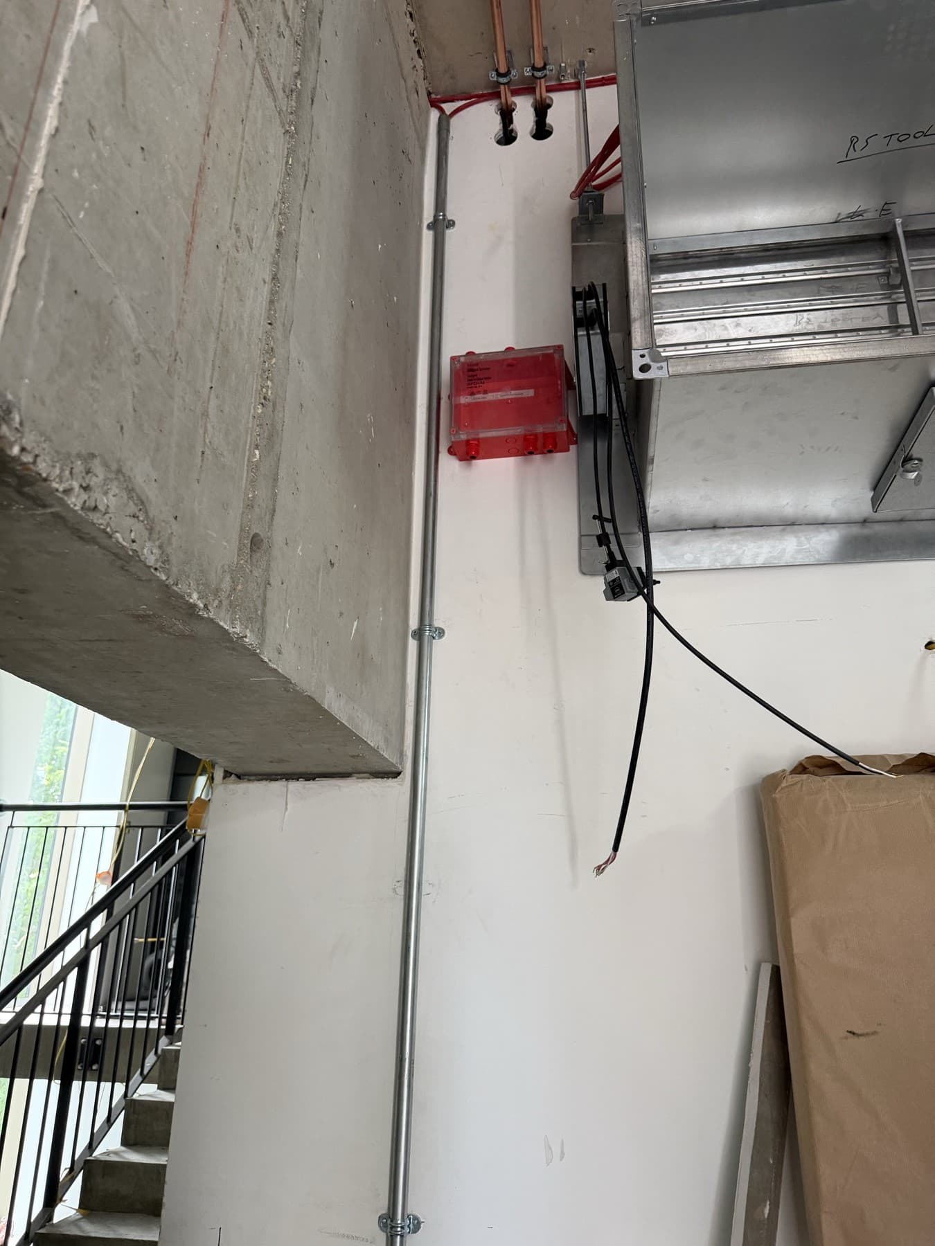 Galvanised conduit riser feeding a red MSFD connection box at 155 Tooley Street