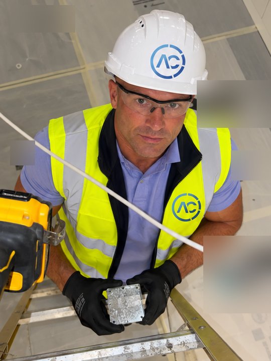 Alpha Controls engineer on a ladder during a VAV installation, running Belden cable through the ceiling void