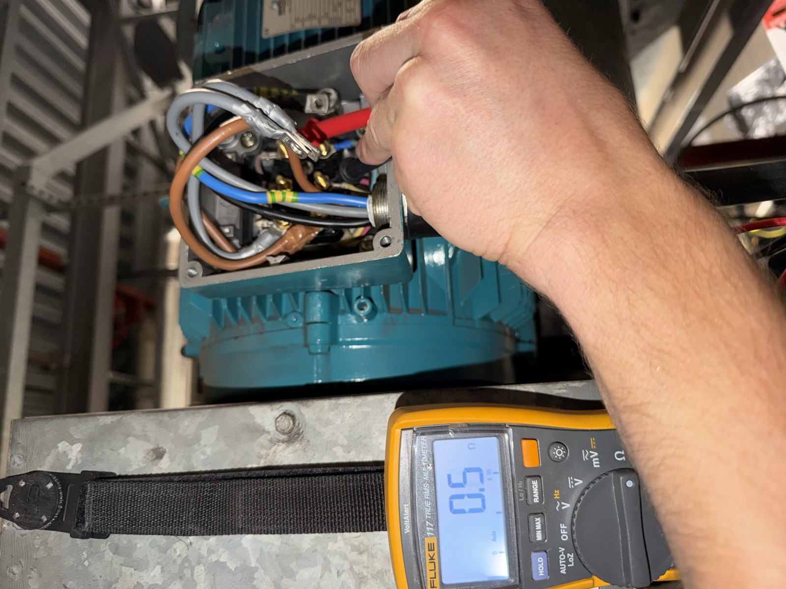 Fluke multimeter showing approximately 0.5 ohm during motor winding resistance test