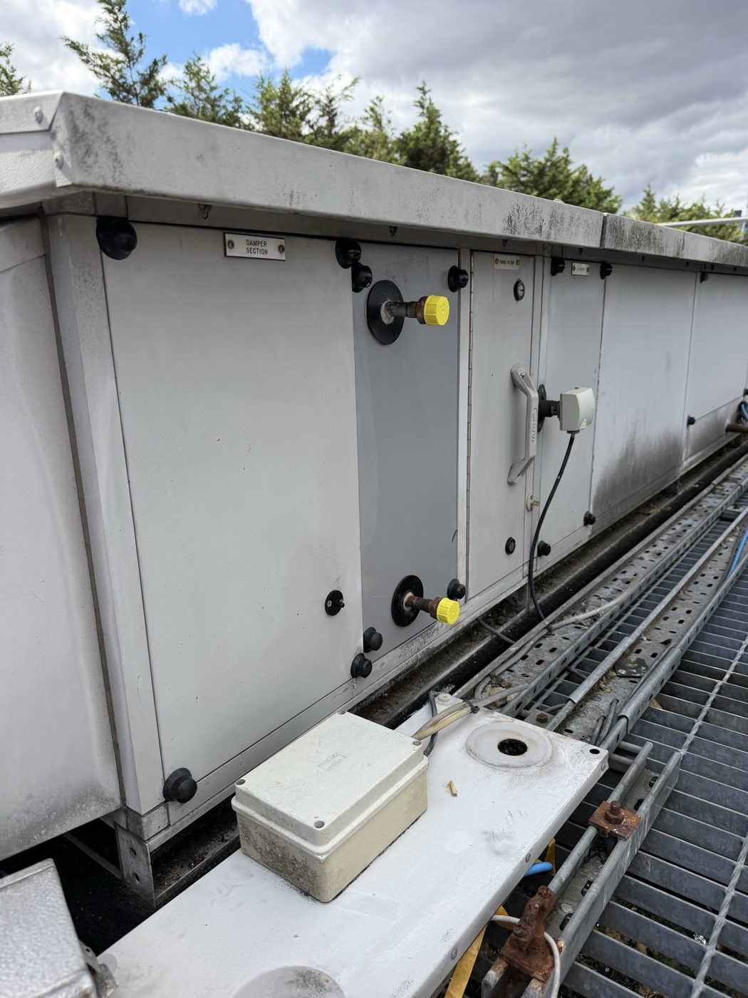 Damper section of a rooftop air handling unit with a field device enclosure on the casing and an existing junction box on the cable tray below